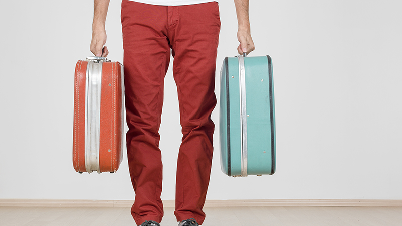 Man in red pants carrying a red suitcase and a blue suitcase